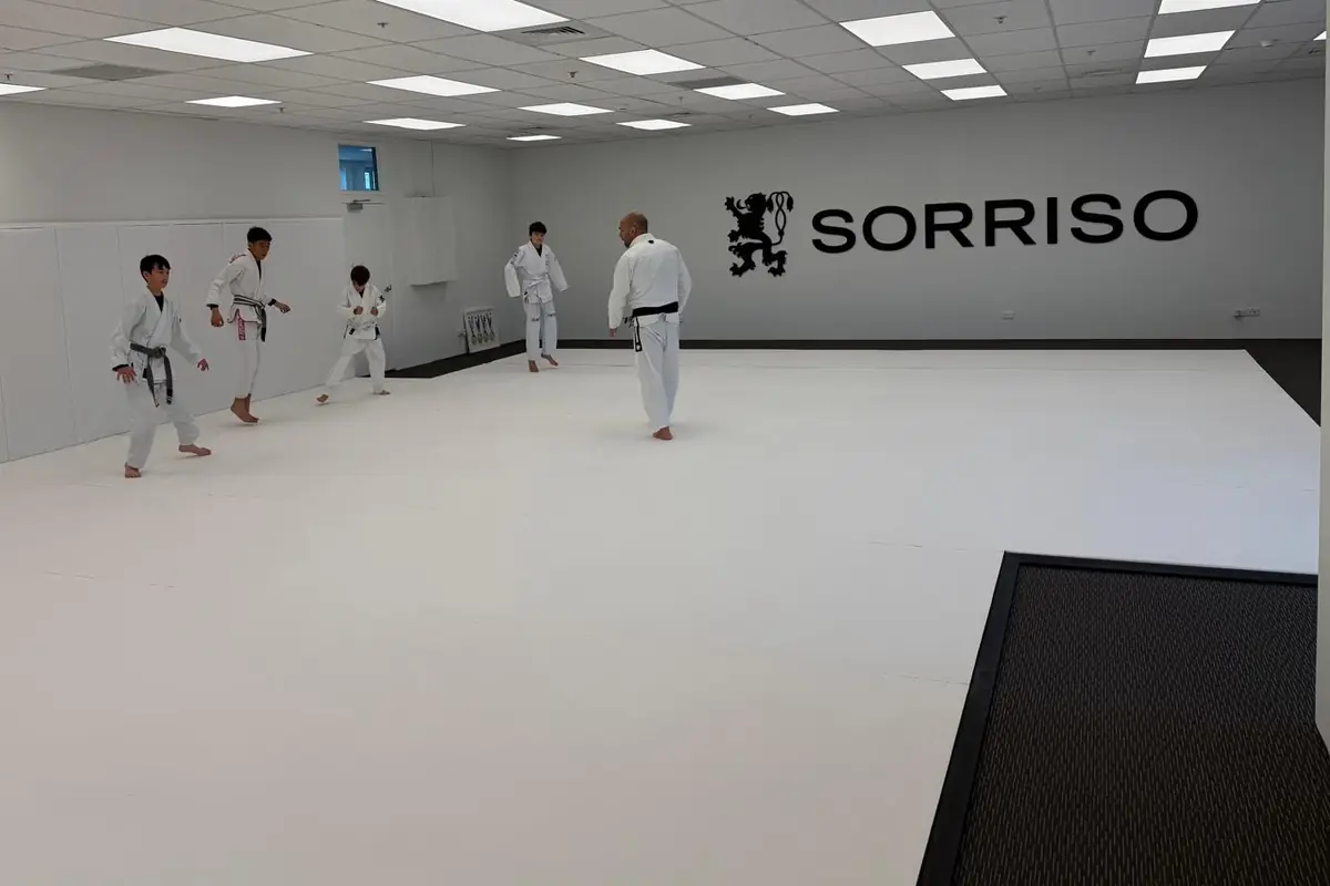 Kids warming up with their coach on the white mats at Sorriso BJJ Botany in Botany Town Centre